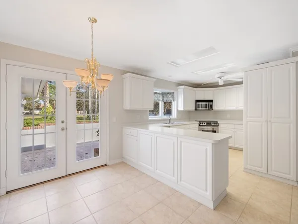 a kitchen with stainless steel appliances kitchen island granite countertop a refrigerator a sink a stove and white cabinets