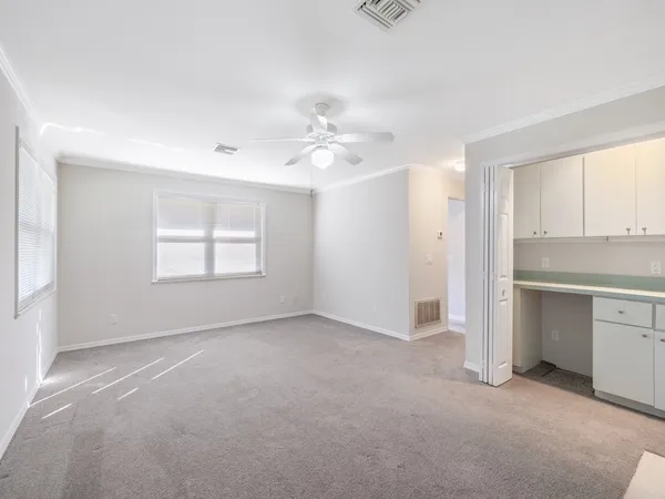an empty room with windows and chandelier fan