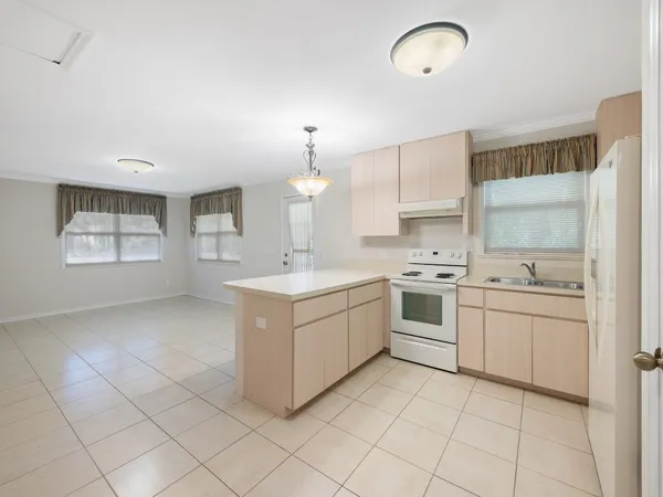 a kitchen with a sink a stove a refrigerator and white cabinets