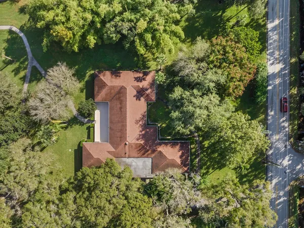 an aerial view of a house with a yard and trees all around