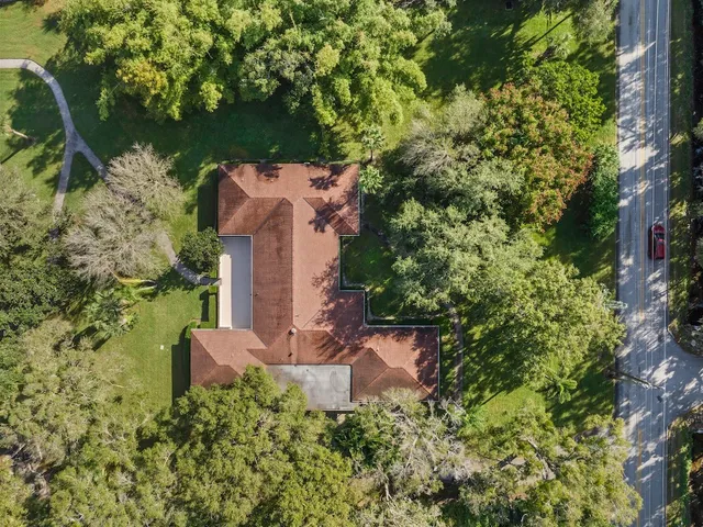 an aerial view of a house with a yard and trees all around