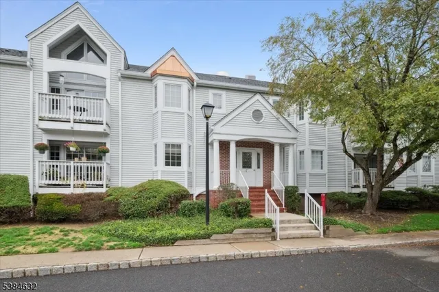 a view of a white house with large windows and a tree