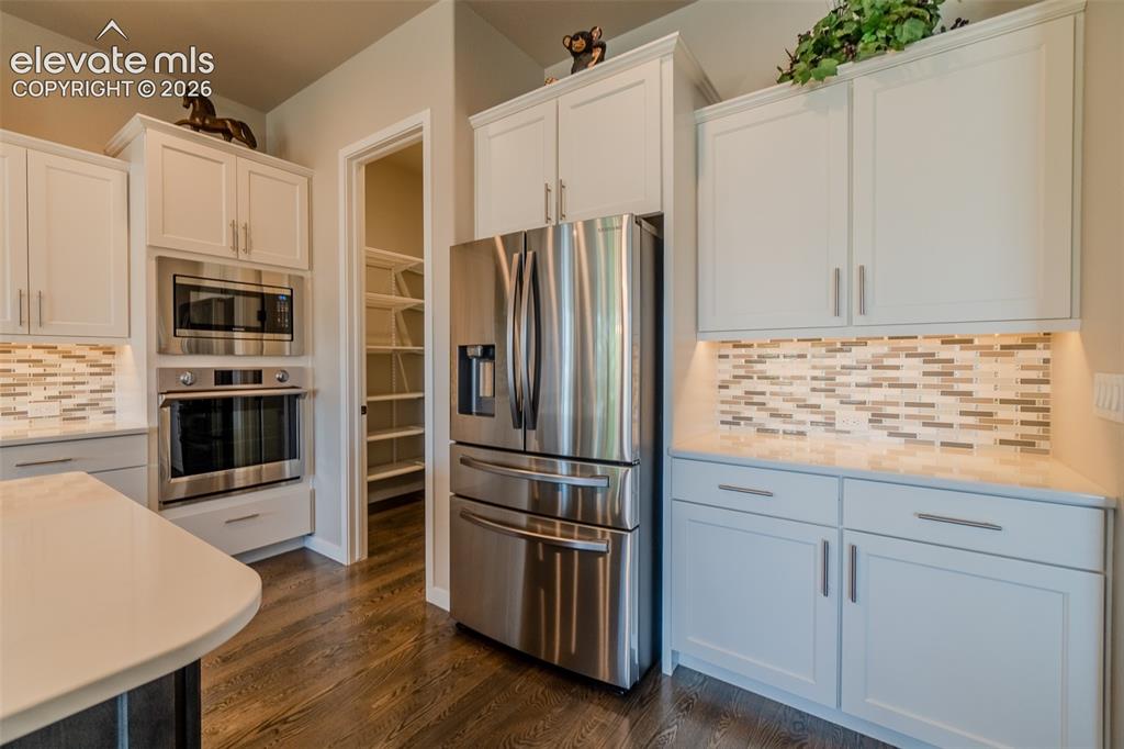 1061 Native Dancer Terrace Colorado Springs, CO 80921 - Photo 15 of 50 Modern kitchen featuring white shaker cabinetry, stainless steel appliances, and wood-finish flooring