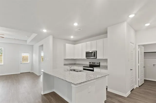 a kitchen with kitchen island a sink a stove a microwave a center island and a window