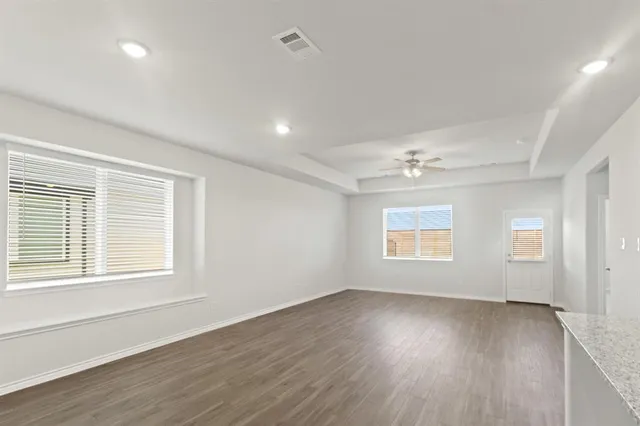 an empty room with wooden floor and windows
