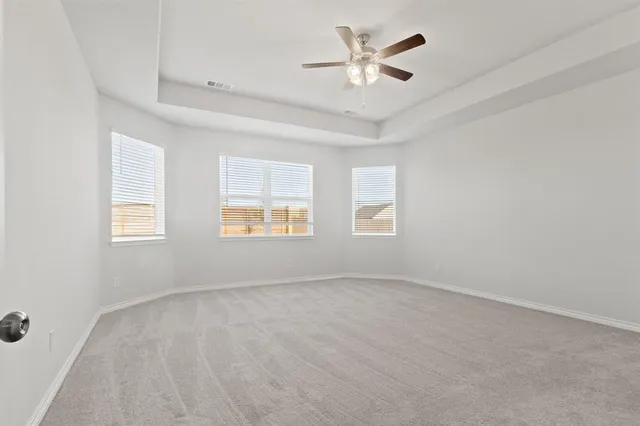an empty room with windows and ceiling fan