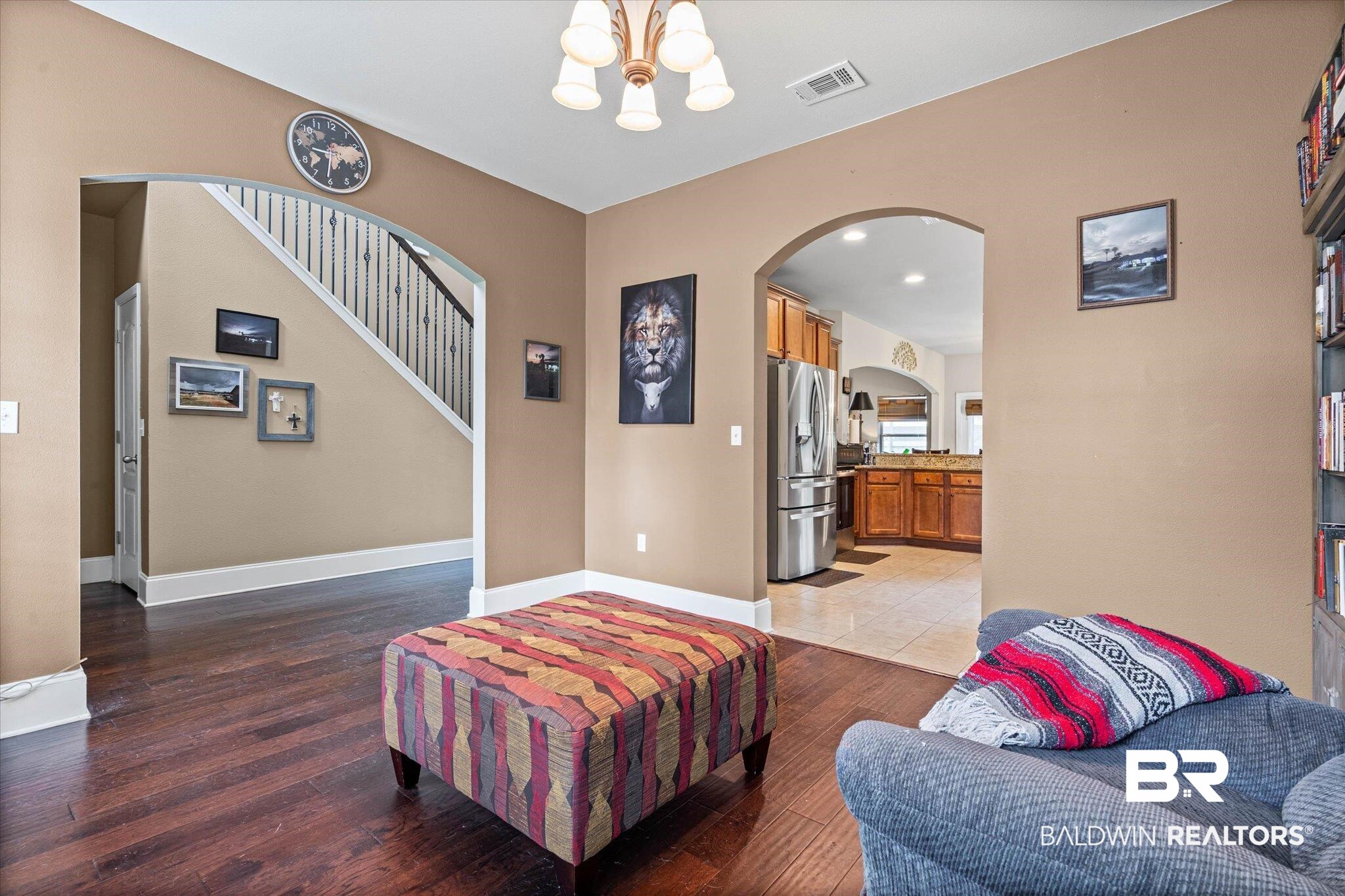 585 Sheffield Avenue Foley, AL 36535 - Photo 4 of 45 Interior space featuring dark wood-finish flooring, arched doorways, a staircase with white risers and dark balusters, a ceiling-mounted light fixture, and neutral-toned wall paint