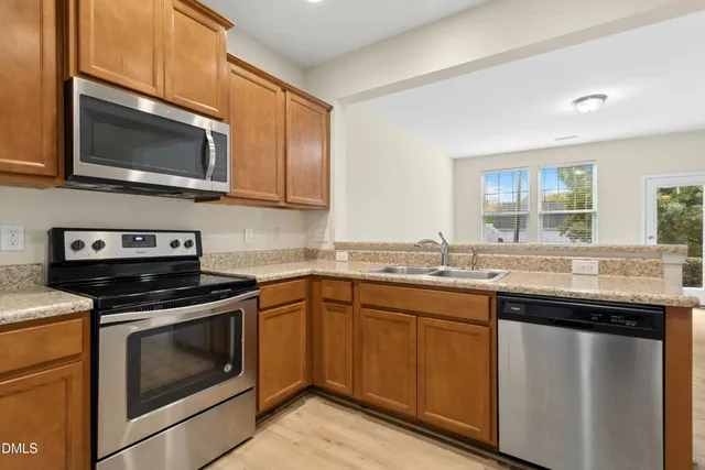 a kitchen with stainless steel appliances granite countertop a sink and a microwave with wooden floor