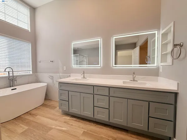 a bathroom with double vanity sinks a large mirror and a bathtub