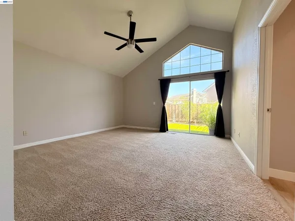 an empty room with a window and a ceiling fan