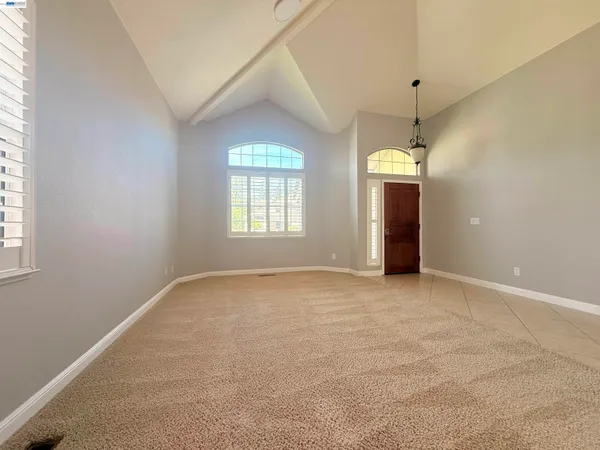 an empty room with windows and chandelier fan