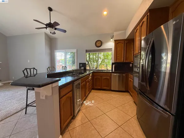 a kitchen with stainless steel appliances granite countertop a refrigerator a sink a stove a dining table and chairs