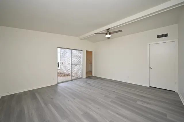 a view of an empty room with wooden floor and a window