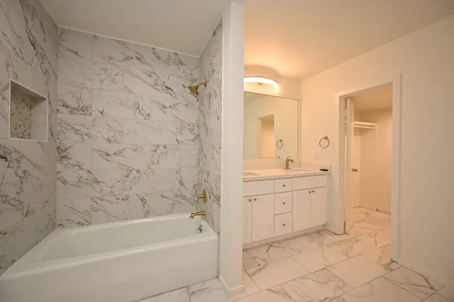 a bathroom with a granite countertop sink a mirror and a bathtub