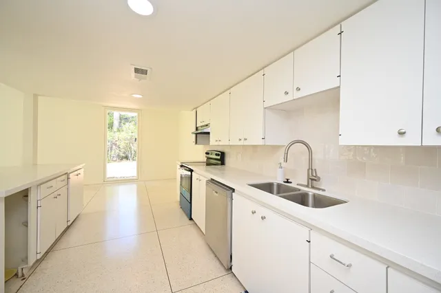 a kitchen with white cabinets a sink dishwasher and a stove with wooden floor