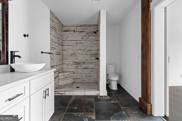 a bathroom with a granite countertop sink a toilet and shower