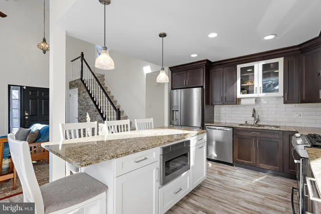 a kitchen with stainless steel appliances granite countertop a sink a stove and a wooden floors
