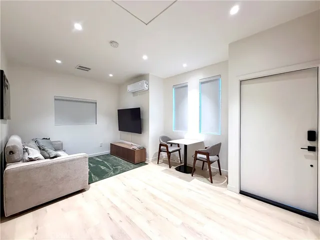 a living room with furniture a flat screen tv and a refrigerator