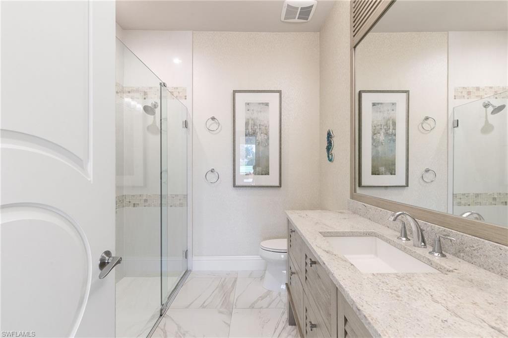 5903 Burnham Road Naples, FL 34119 - Photo 18 of 38 a bathroom with a granite countertop sink toilet and shower