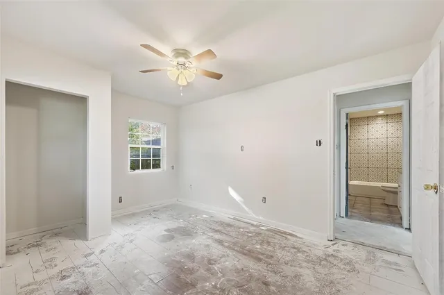 an empty room with windows and fan