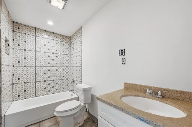 a bathroom with a granite countertop sink a toilet a mirror and shower