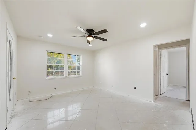an empty room with a ceiling fan and window