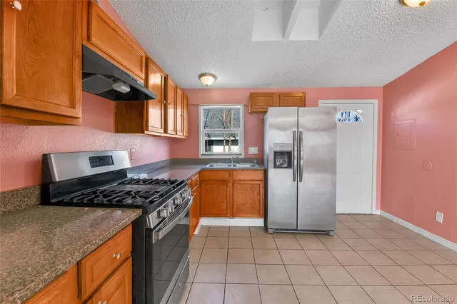 a kitchen with granite countertop a stove a refrigerator and a cabinets