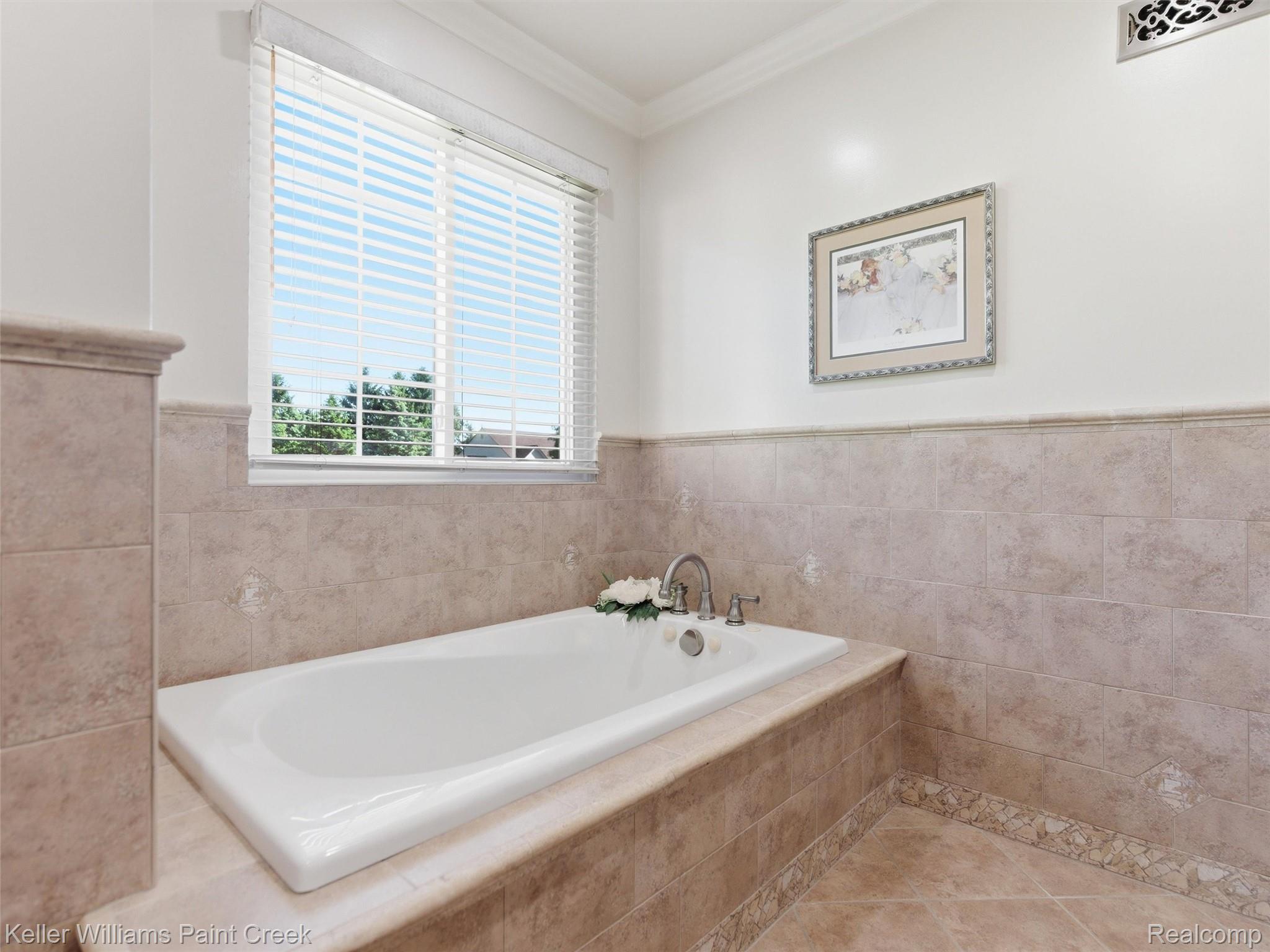 2842 Manorwood Road Troy, MI 48085 - Photo 49 of 72 Built-in soaking tub with deck-mounted faucet, surrounded by tiled walls with accent trim