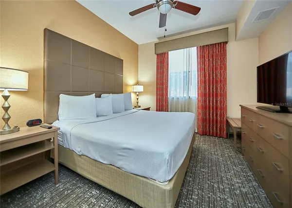 a bedroom with a bed and a flat tv screen on dresser