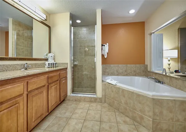 a spacious bathroom with a granite countertop tub sink shower and mirror
