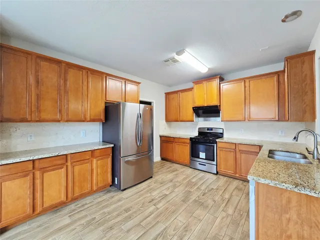 a kitchen with stainless steel appliances granite countertop a refrigerator a sink dishwasher stove and oven