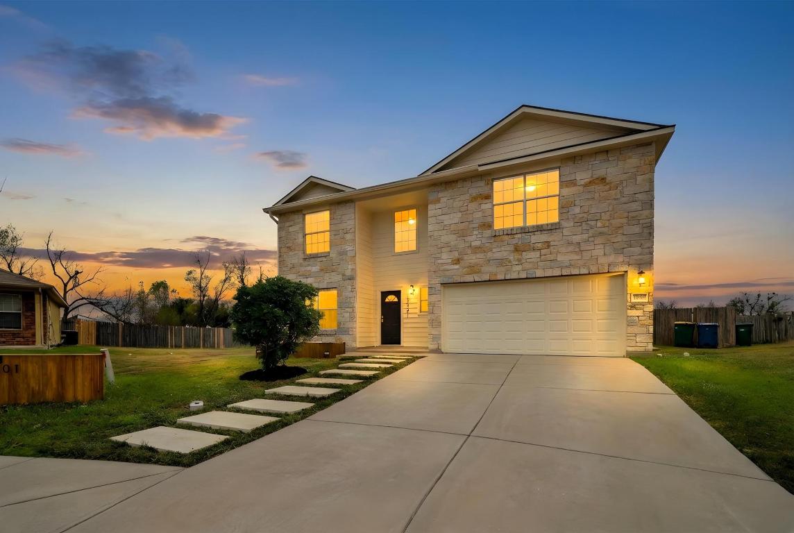 Traditional home featuring stone siding, an attached garage, and driveway