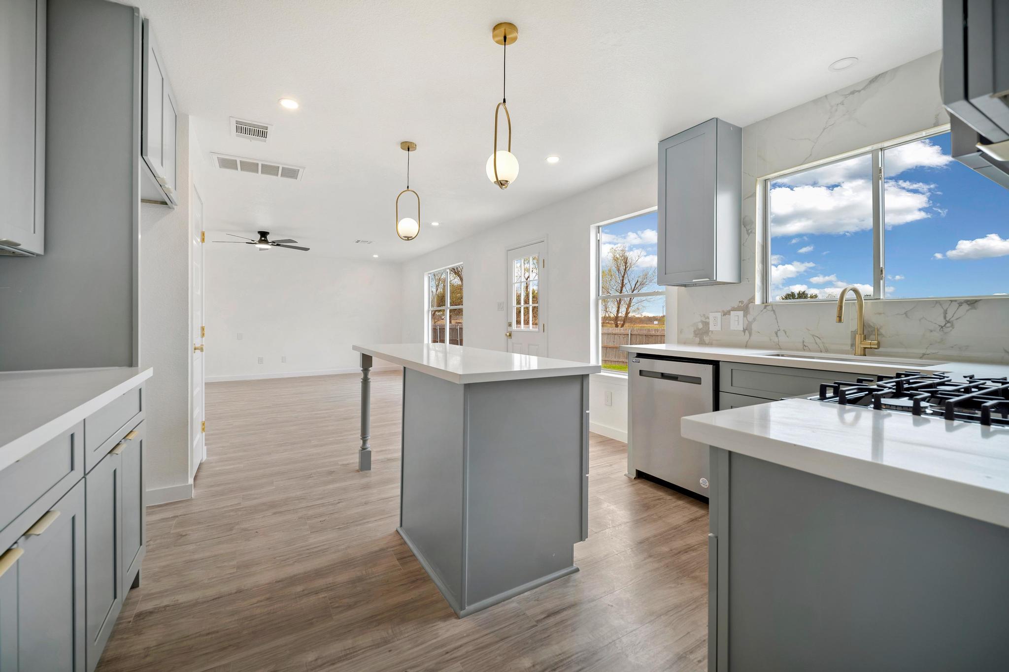 13501 Sierra Wind Lane Elgin, TX 78621 - Photo 11 of 31 Kitchen with gray cabinetry, decorative light fixtures, a kitchen island, stainless steel appliances, and light wood-style floors