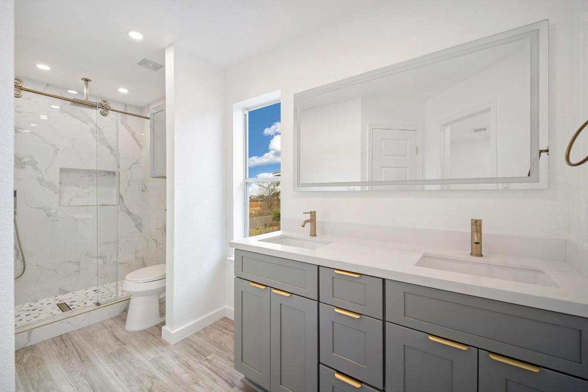 13501 Sierra Wind Lane Elgin, TX 78621 - Photo 18 of 31 Bathroom with double vanity, a marble finish shower, recessed lighting, and light wood finished floors
