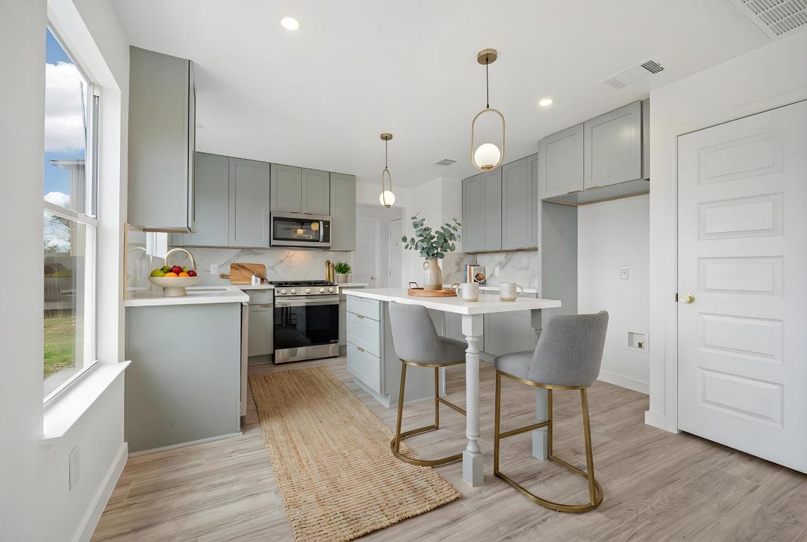 13501 Sierra Wind Lane Elgin, TX 78621 - Photo 8 of 31 Kitchen featuring gray cabinets, decorative light fixtures, appliances with stainless steel finishes, a kitchen breakfast bar, and recessed lighting