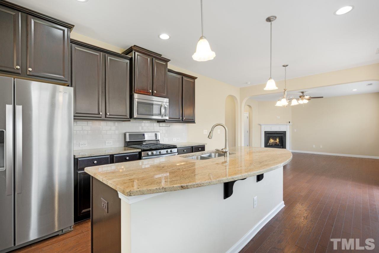 2433 Pilsley Road Apex, NC 27539 - Photo 11 of 28 a kitchen with stainless steel appliances a sink a stove a refrigerator a center island and cabinets