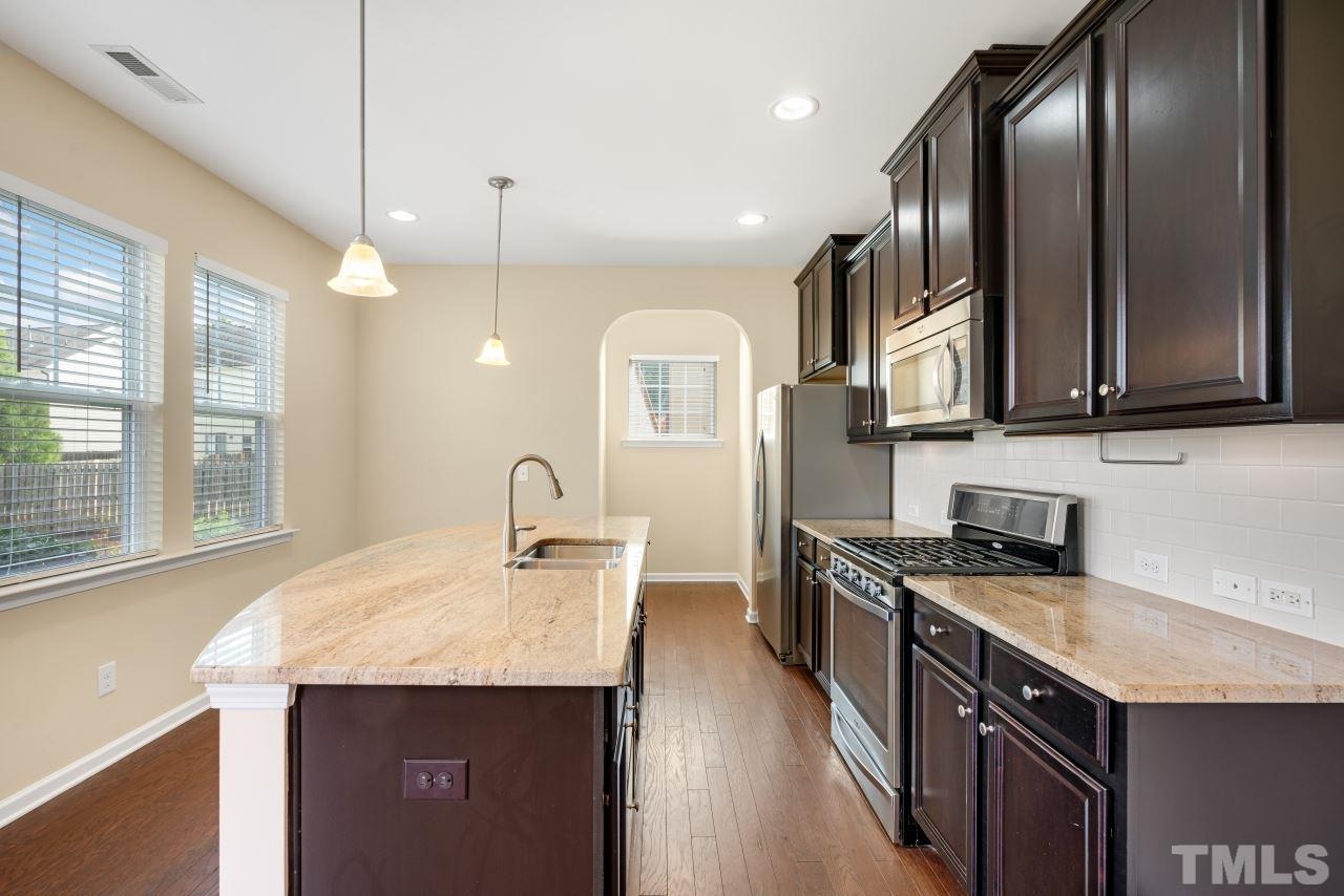 2433 Pilsley Road Apex, NC 27539 - Photo 13 of 28 a kitchen with stainless steel appliances granite countertop a sink a stove and a wooden floors