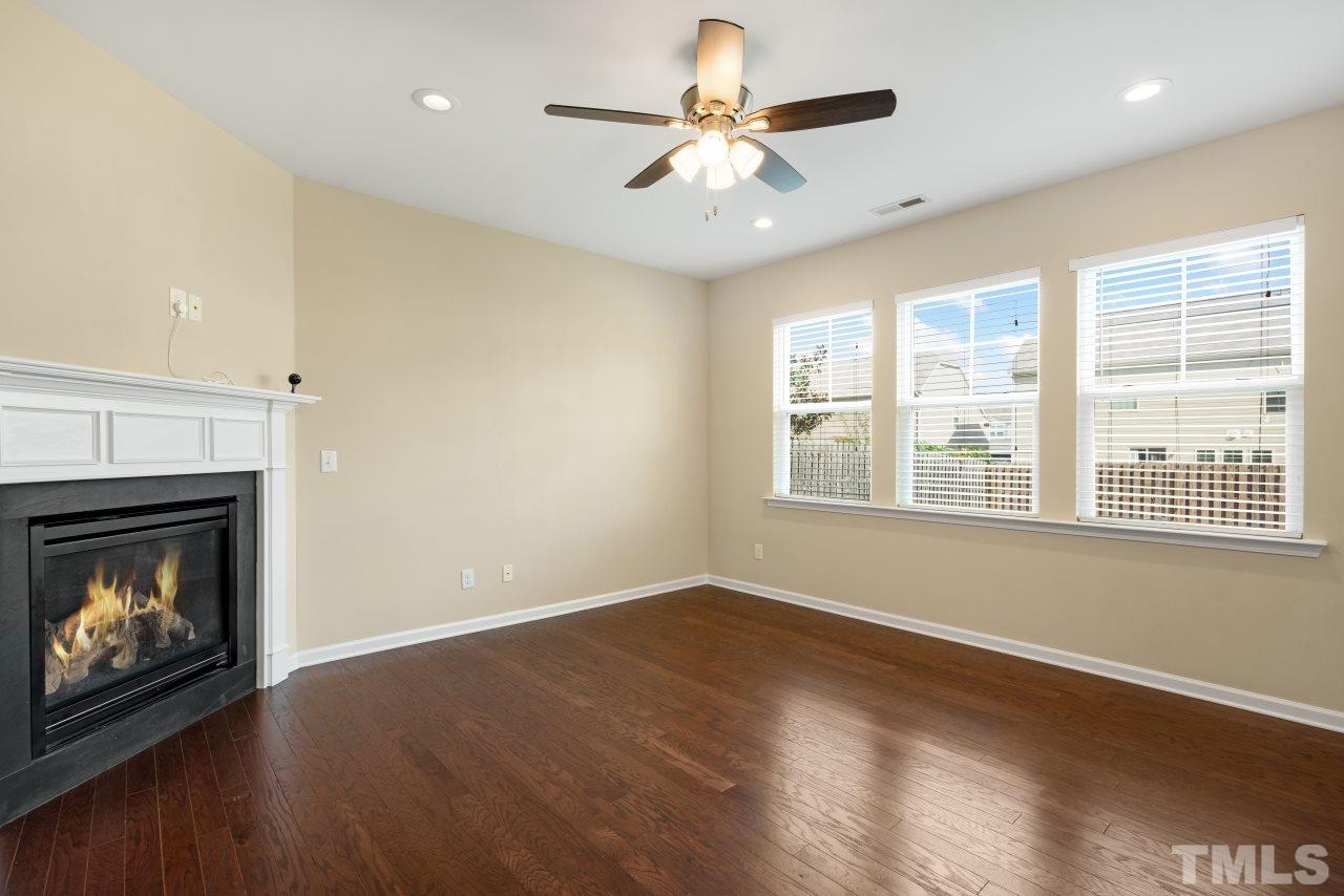 2433 Pilsley Road Apex, NC 27539 - Photo 7 of 28 a view of an empty room with wooden floor fireplace and a window