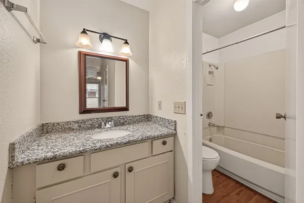 a view of an empty room with wooden floor and a ceiling fan