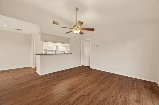 a view of a room with wooden floor a ceiling fan and a window