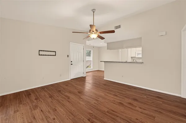 a view of a room with wooden floor a ceiling fan and windows