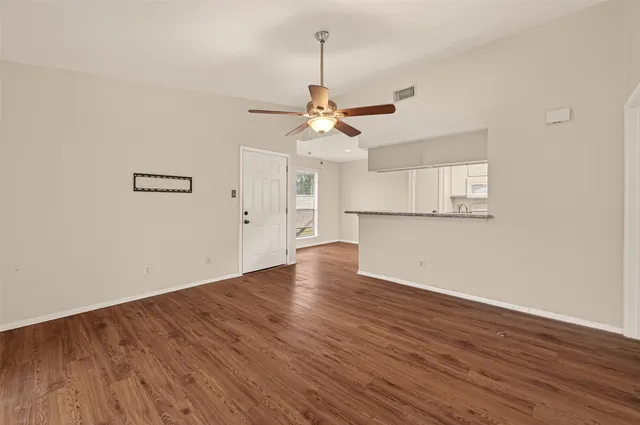 a view of a room with wooden floor a ceiling fan and windows