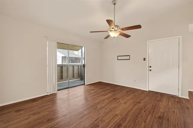an empty room with wooden floor fan and windows