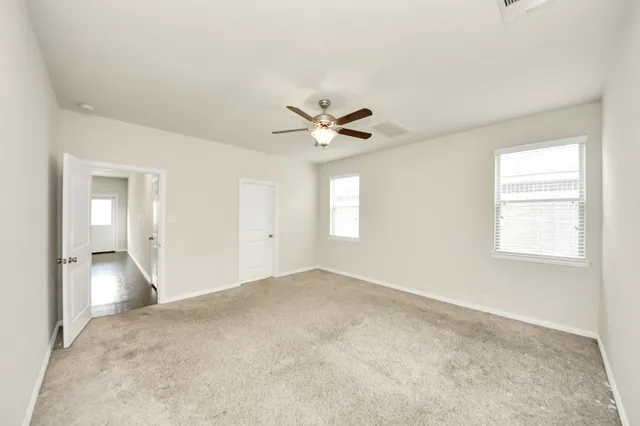 an empty room with closet and ceiling fan