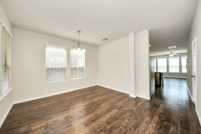a view of an empty room with a window and wooden floor