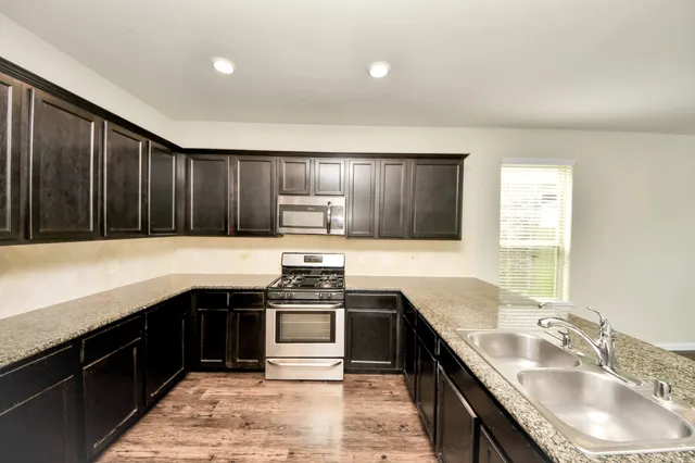 a kitchen with stainless steel appliances granite countertop a sink stove and refrigerator