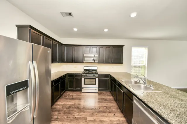 a kitchen with granite countertop a refrigerator and a stove top oven