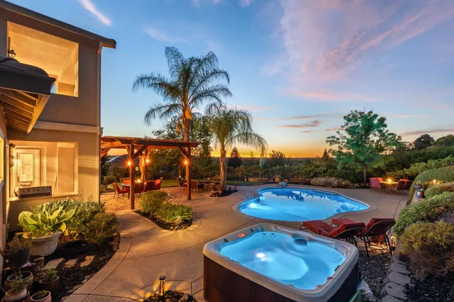 a kitchen with stainless steel appliances granite countertop a refrigerator a stove top oven a sink dishwasher a dining table and chairs with wooden floor