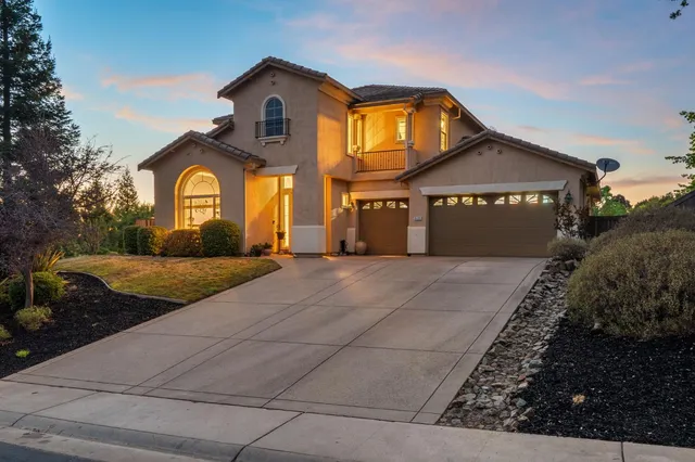 a front view of a house with garage and plants