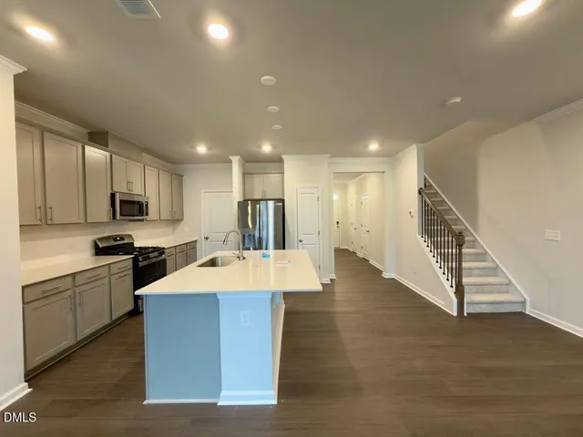 a large kitchen with stainless steel appliances kitchen island a stove a sink dishwasher and a refrigerator with wooden floor